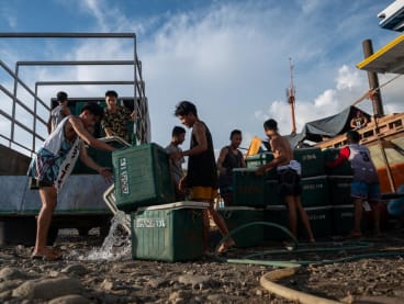 Workers unload fishing coolers at a port in Masinloc, Zambales province, Philippines on Sept 26, 2023.