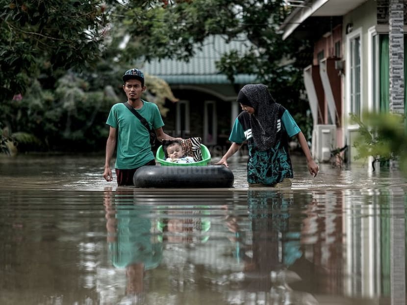 A couple in Permatang Pauh wade through the flood with their baby using an improvised float on Nov 6, 2017. Photo: The Malaysian Insight