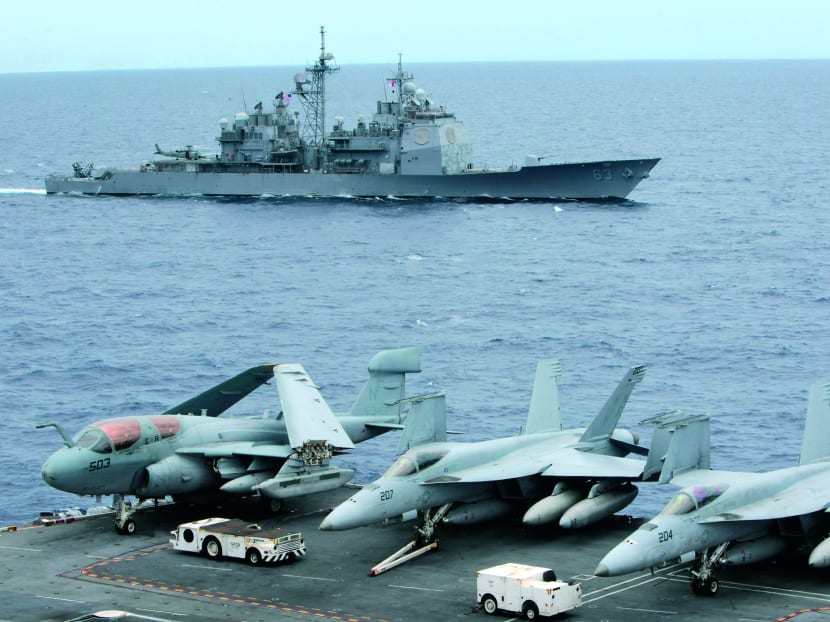 U.S fighter jets on standby at the upper deck of a USS George Washington aircraft carrier while a U.S. Cowpens ship pass during a media tour at the South China Sea, 170 nautical miles from Manila September 3, 2010. Photo: Reuters