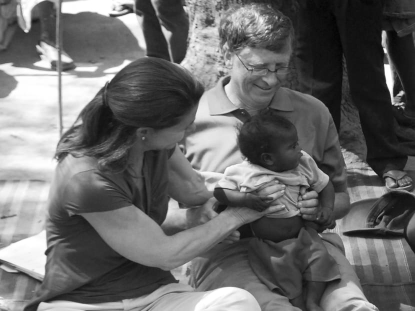 Mr Bill Gates and his wife Melinda holding a child during their visit to a slum area in India in 2011. With an income cap policy, the wealthy would compete to outdo others in giving to the best charities. Photo: Reuters