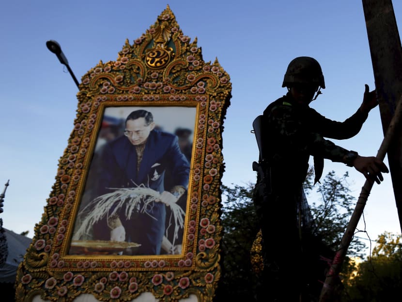 A soldier climbs a barricade in front of a picture of Thailand's King Bhumibol Adulyadej as his unit dismantles an anti-government encampment in central Bangkok in this May 23, 2014 file photo. Photo: Reuters