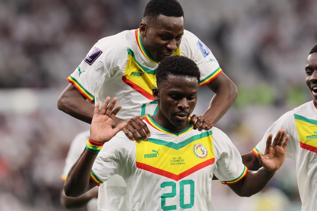 Senegal's forward #20 Bamba Dieng celebrates with teammates after scoring his team's third goal during the Qatar 2022 World Cup Group A football match between Qatar and Senegal at the Al-Thumama Stadium in Doha on Nov 25, 2022.
