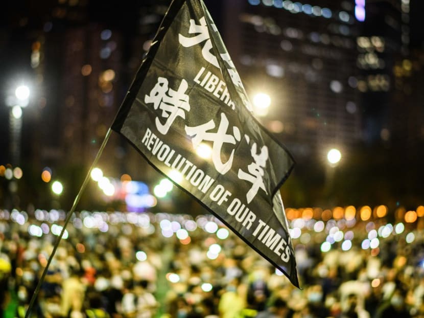 Attendees raise a flag that reads 'Liberate Hong Kong Revolution Of Our Times' during a candlelit remembrance in Victoria Park in Hong Kong on June 4, 2020.