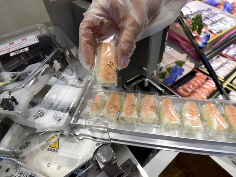An employee of Japan's cooked rice processing machine maker SUZUMO demonstrates its automatic sushi wrapping machine at the International Food Machinery and Technology Exhibition in Tokyo. Photo: AFP