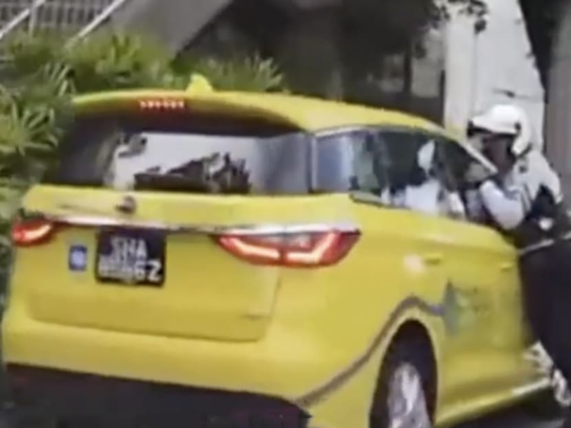 Screengrab from social media showing a traffic police officer reaching into a taxi. He was trying to turn off the taxi's ignition button. Screengrab from social media showing a traffic police officer reaching into a taxi. He was trying to turn off the taxi's ignition button.