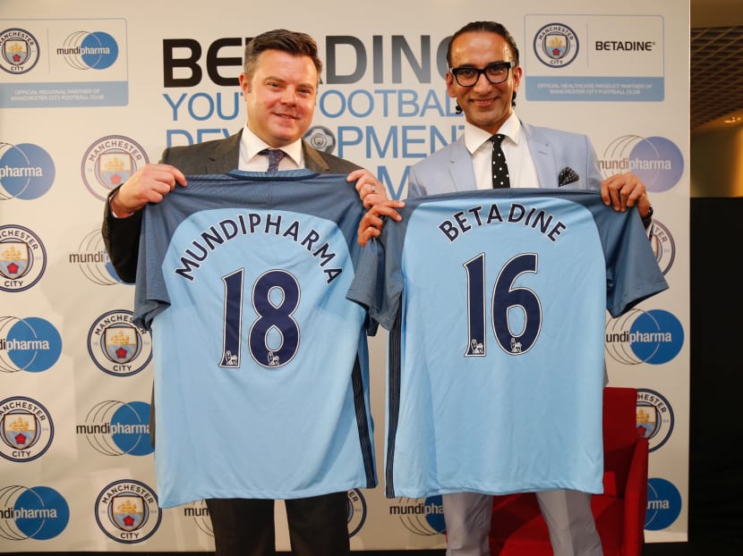 Damian Willoughby, Senior VP of Partnerships for City Football Group and Raman Singh, CEO of Mundipharma holding up Manchester City jerseys with Betadine, a healthcare product of Mundipharma. Photo: Najeer Yusof