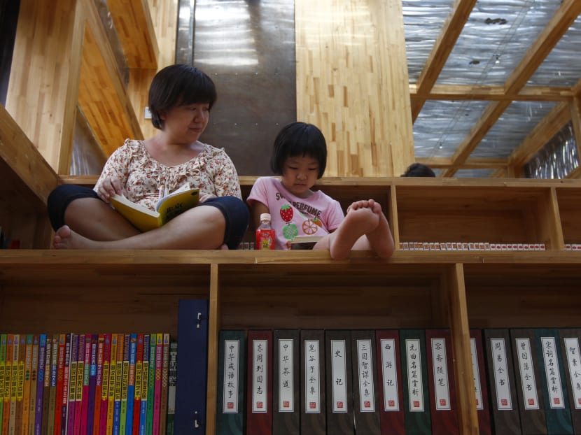A woman (L) looks at her daughter as they read books at a library in Beijing, China. Artificial intelligence (AI) software developed by Alibaba Group has performed better than humans in a global reading comprehension test, the first time that machines have outperformed people. Photo: Reuters