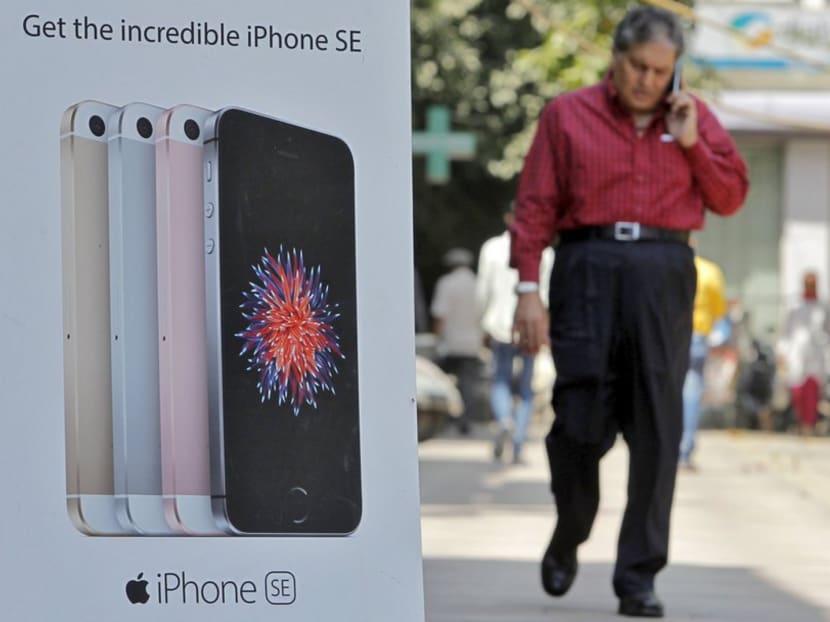 A man speaks on his mobile phone as he walks past an Apple iPhone SE advertisement billboard in a street in New Delhi, India, April 25, 2016. Photo: REUTERS