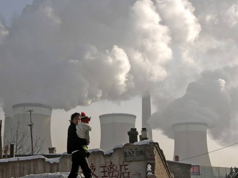 A woman and her baby walking past a coal-fired power plant on the outskirts of Datong, Shanxi province. Photo: Reuters