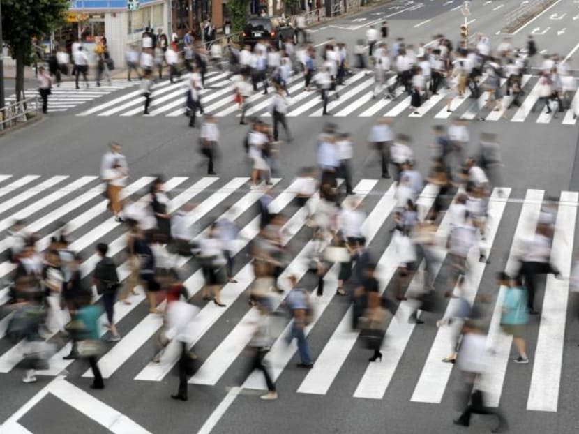 Japanese workers crossing a road near JR Tamachi station in Tokyo's Minato Ward. In a bid to change long-held working behaviours, Japan introduced a new labour reform law in late June, setting a legal cap on overtime work as one of its pillars.