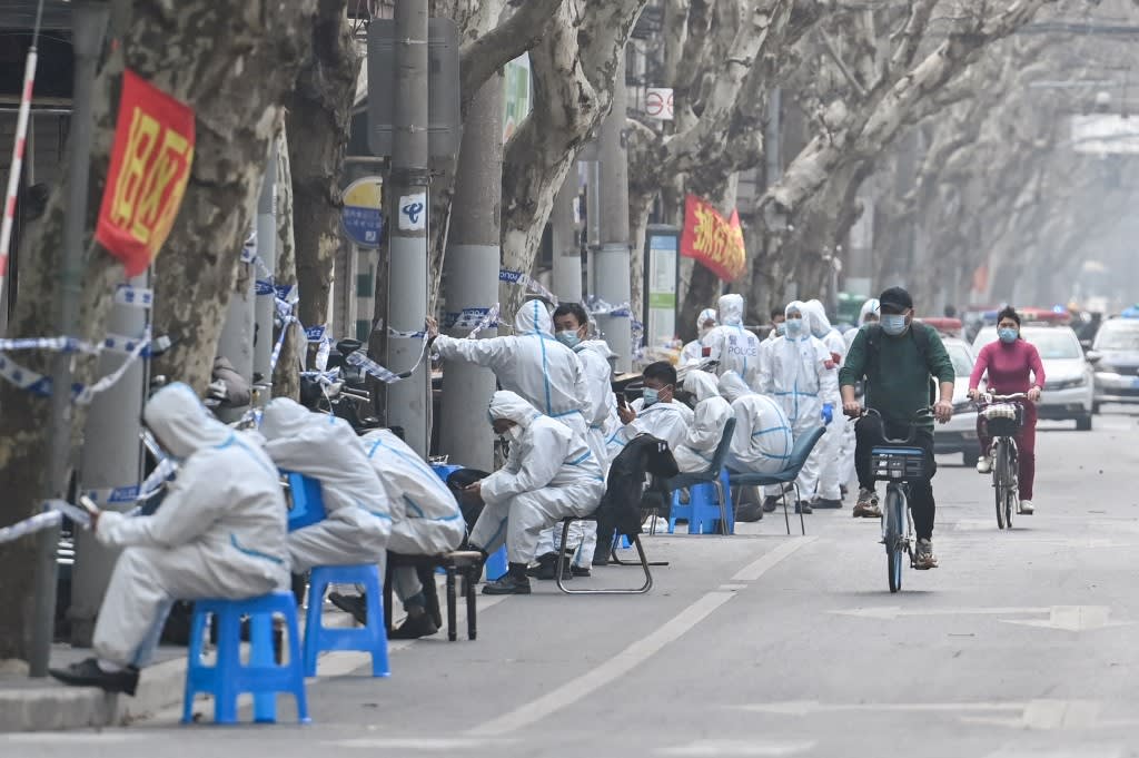 Workers are seen wearing protective clothes next to some lockdown areas after the detection of new cases of Covid-19 in Shanghai on March 14, 2022