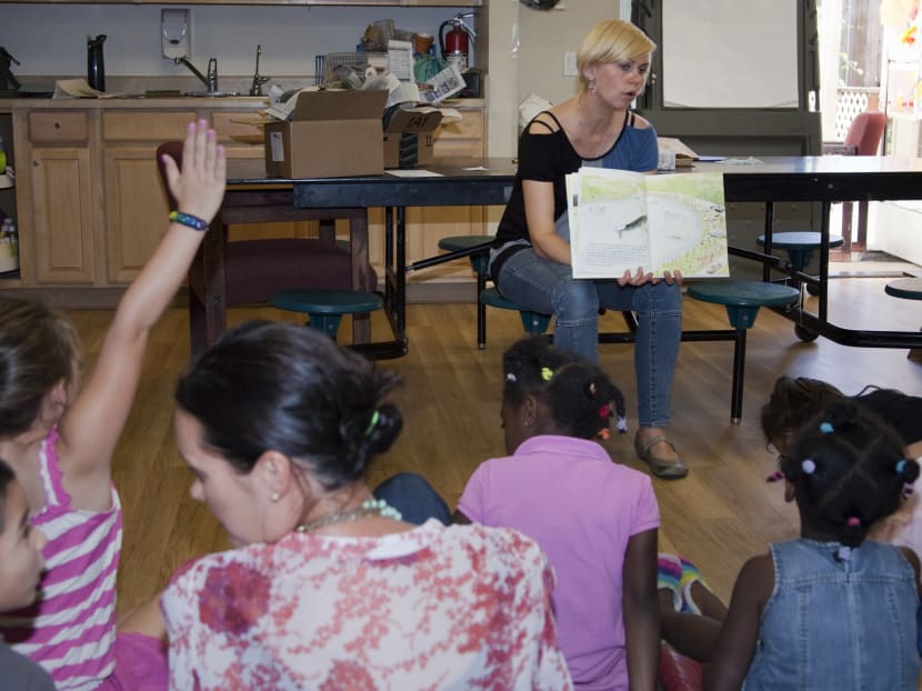 In this June 2014 photo provided by Transition House, a homeless shelter in Santa Barbara, California, Ms Nicole Janowicz, a member of Transition House children’s program staff, reads a story to children before dinner as part of Transition House’s Technology and Literacy for Children program. Photo: AP