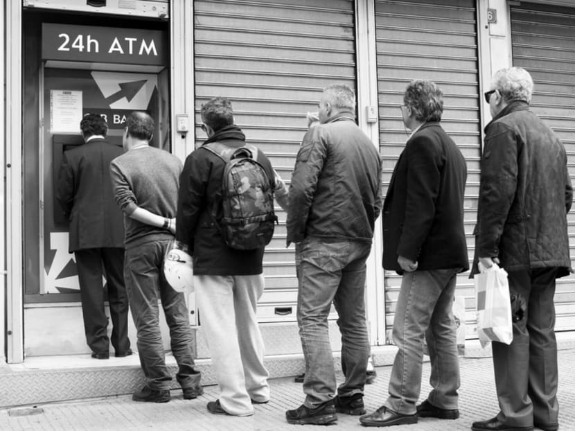Customers queueing to withdraw money from ATMs in Greece. One still might think that it makes sense to hold cash directly, rather than holding an asset with a negative return. But holding cash can be risky, as Greek savers, worried about the safety of their bank deposits, learnt after stuffing it into their mattresses and walls.
Photo: Bloomberg