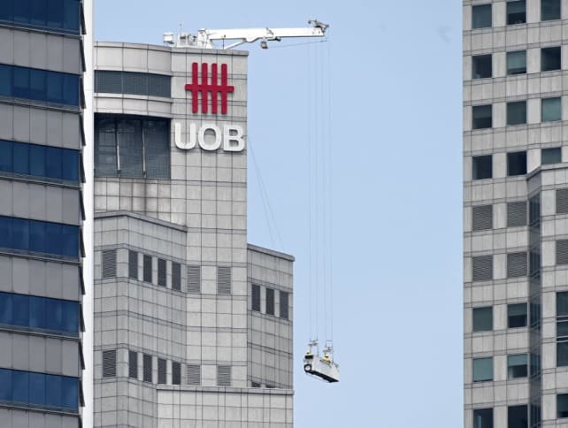 Workers are hoisted on a gondola cleaning the UOB bank building in Singapore on Aug 29, 2019.