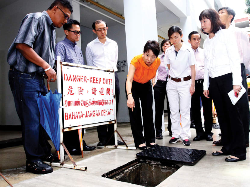 Second Minister for the Environment and Water Resources Grace Fu 
(in orange) being shown a drainage system where there is likely to be a mosquito  breeding ground, during a site visit to MacPherson estate yesterday. PHOTO: ERNEST CHUA