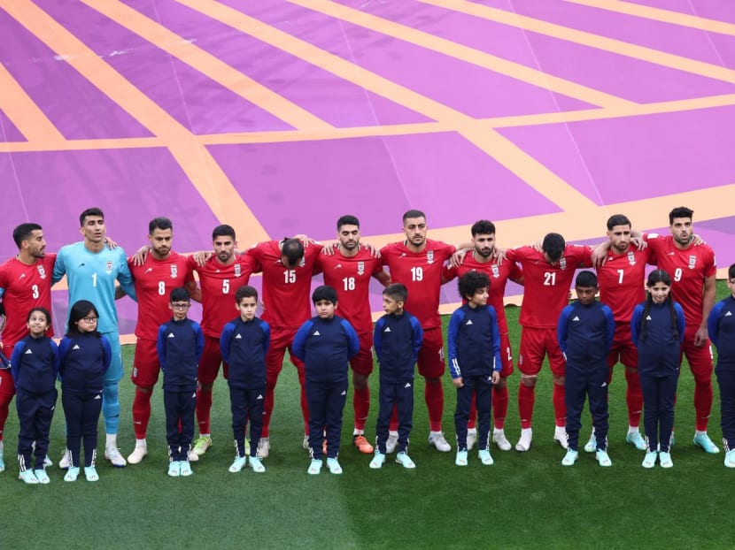 The players were silent as the anthem was played at the Khalifa International Stadium, where Iranian fans gathered in the stands shouted as the music was played. Some were seen making thumbs-down gestures. The players were silent as the anthem was played at the Khalifa International Stadium, where Iranian fans gathered in the stands shouted as the music was played. Some were seen making thumbs-down gestures.