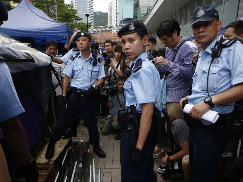 Police officers check the protesters' tents where remain on the sidewalk during an operation outside the Legislative Council in Hong Kong, Saturday, June 13, 2015. Photo: AP