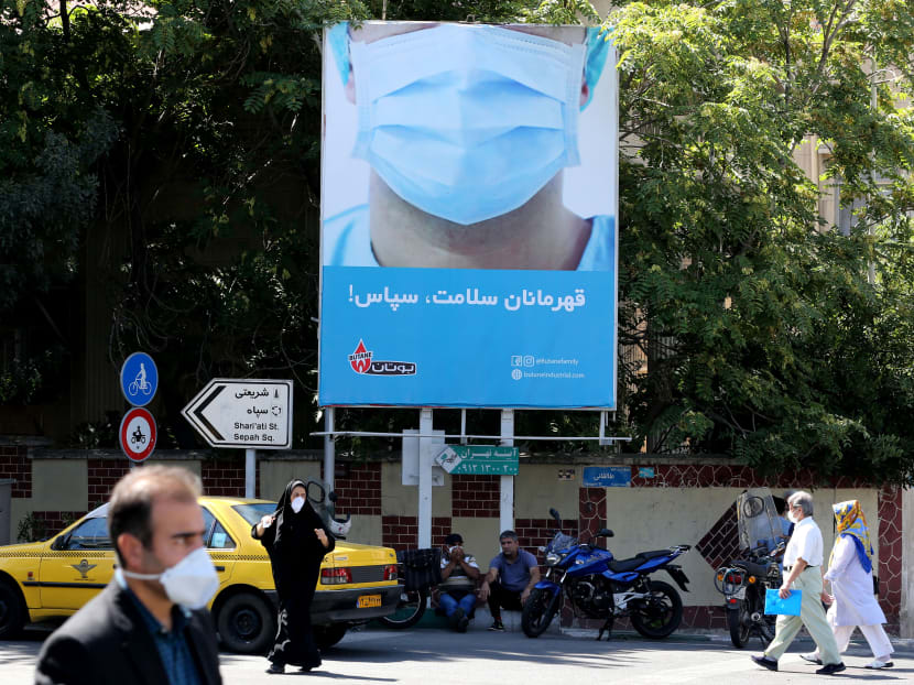 Iranians, wearing protective face masks, walk under a billboard thanking first responders in the capital Tehran on Wednesday, July 22, 2020, during the Covid-19 epidemic.