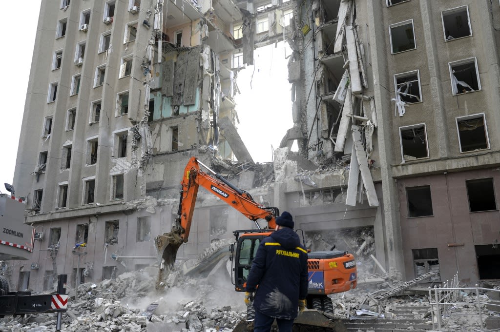 A worker watches an excavator clearing the rubble of a government building hit by Russian rockets in Mykolaiv on March 29, 2022.