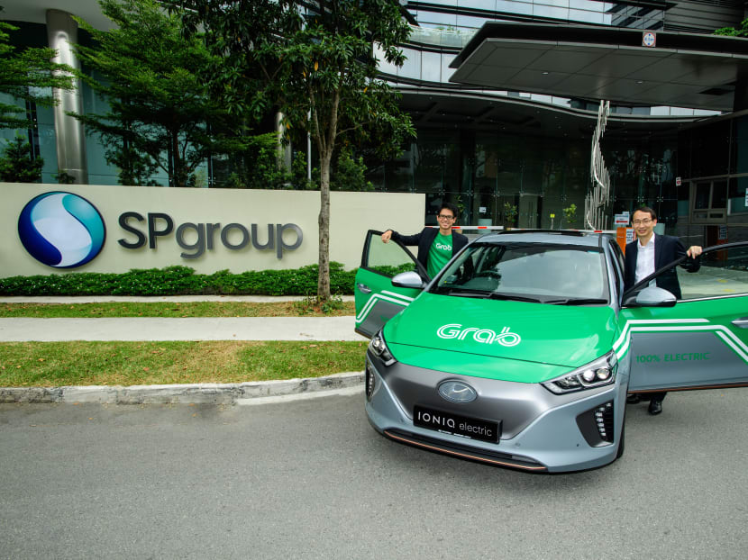 Head of Grab Singapore Lim Kell Jay (left) and SP Group head of strategic development Goh Chee Kiong posing with a fully electric Hyundai Ioniq car.