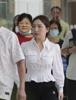 Ding Zhiyan (woman in white blouse) leaving the State Courts on May 14, 2024.