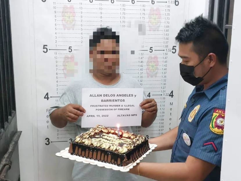 A policeman from the Altavas Municipal Police Station holding up a cake for Allan Barrientos Delos Angeles, who was arrested on the day of his 44th birthday.