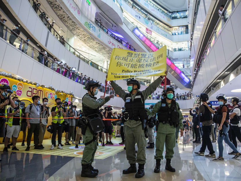 Riot police hold up a warning flag during a demonstration in a mall in Hong Kong on July 6, 2020, in response to a new national security law introduced in the city which makes political views, slogans and signs advocating Hong Kong’s independence or liberation illegal.