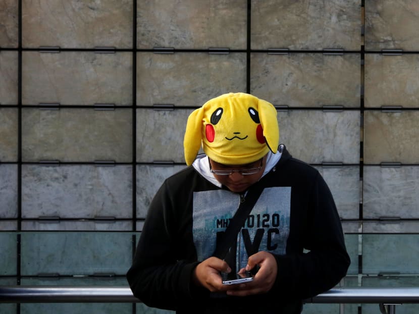 A man wearing a Pikachu hat, a character from Pokemon, plays Pokemon Go during a gathering to celebrate "Pokemon Day" in Mexico City, Mexico on Aug 21, 2016. Photo: Reuters