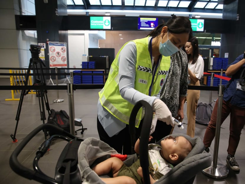 An Immigration and Checkpoints Authority officer taking a baby's temperature at Tuas Checkpoint on Friday (Jan 24), the day the authorities began temperature checks at both land checkpoints.