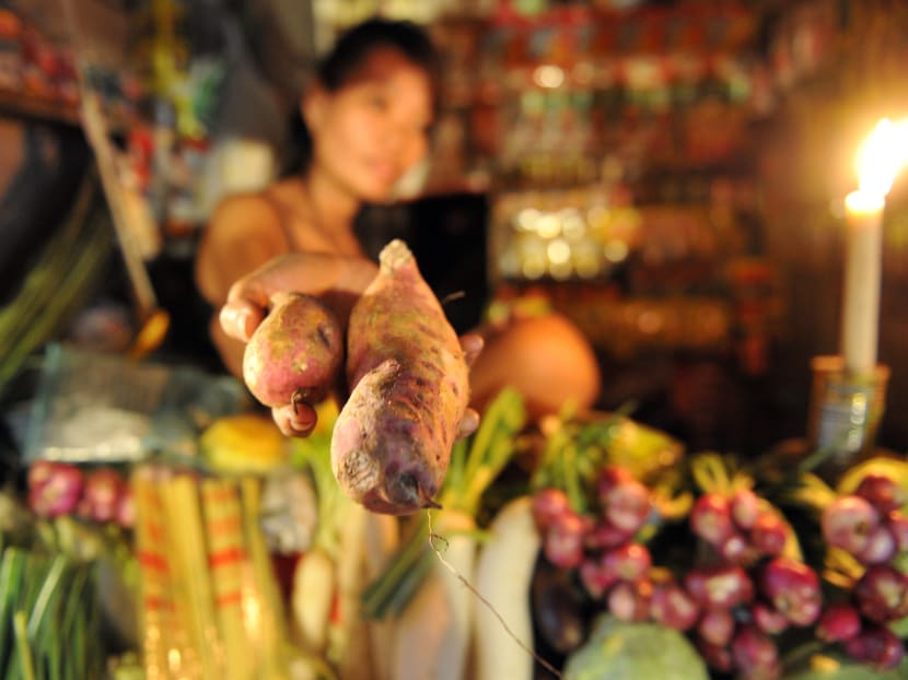 A vendor sells sweet potato at a market near an informal settlers area in Manila. Photo: AFP