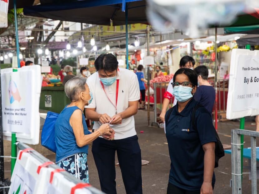 A market-goer gets her NRIC number checked at about 7.30am on April 23, 2020, before entering a wet market at Block 505 Jurong West Street pictured here.