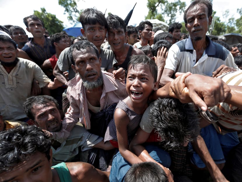 A boy is pulled to safety as Rohingya refugees scuffle while queueing for aid at Cox's Bazar, Bangladesh. Photo: Reuters