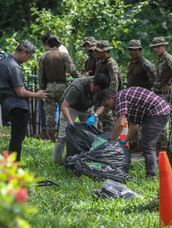 Police and workers filling trash bags with items retrieved from inside a drain along a footpath on Hume Avenue on May 25, 2023. More than 30 bags were seen filled and loaded into a waste management vehicle. 