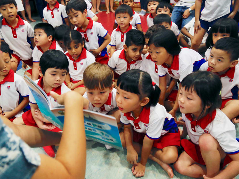 Maj Tan (left) reading ‘Papa Goes to Sea’ to students at a PCF Sparkletots Preschool in Bishan yesterday. Maj Tan says the books are a good opportunity for navy officers and their children to bond over the pictures in the books of what the parents do out at sea, and why they do it. Photo: Najeer Yusof