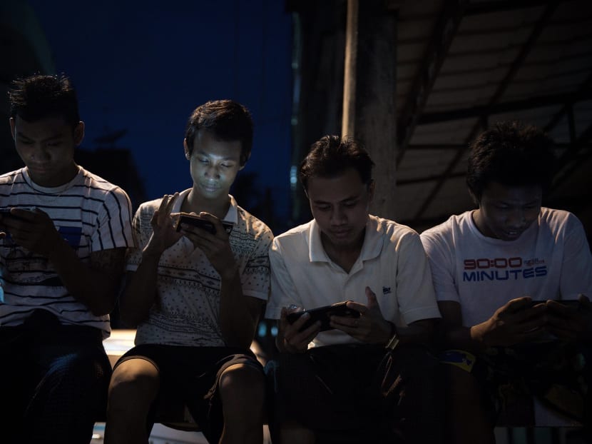 Young men browsing their smartphones as they sit in a street in Yangon. More than 100,000 people have turned to an app designed in Myanmar aimed at tackling some of Asia’s worst maternal mortality rates.