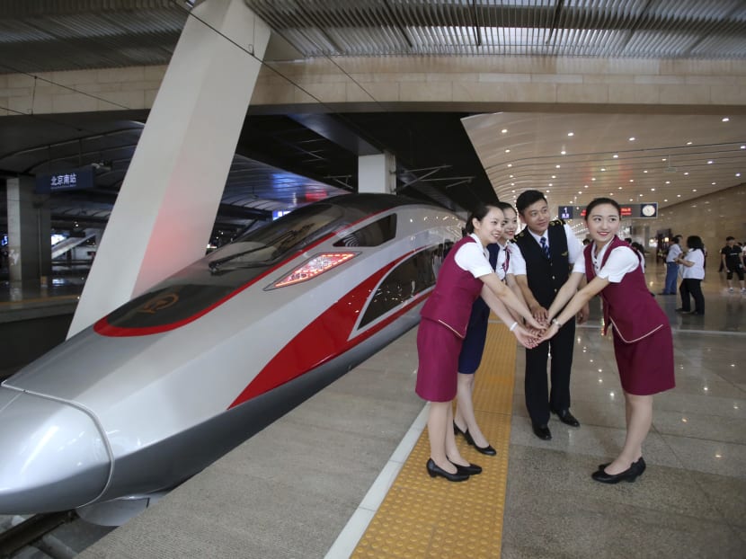 A file photo shows railway workers posing for photos with the Fuxing, China's latest high speed train capable of reaching 400kmh during its maiden service from Beijing. China is relaunching the world's fastest bullet trains in September 2017. Photo: Chinatopix via AP