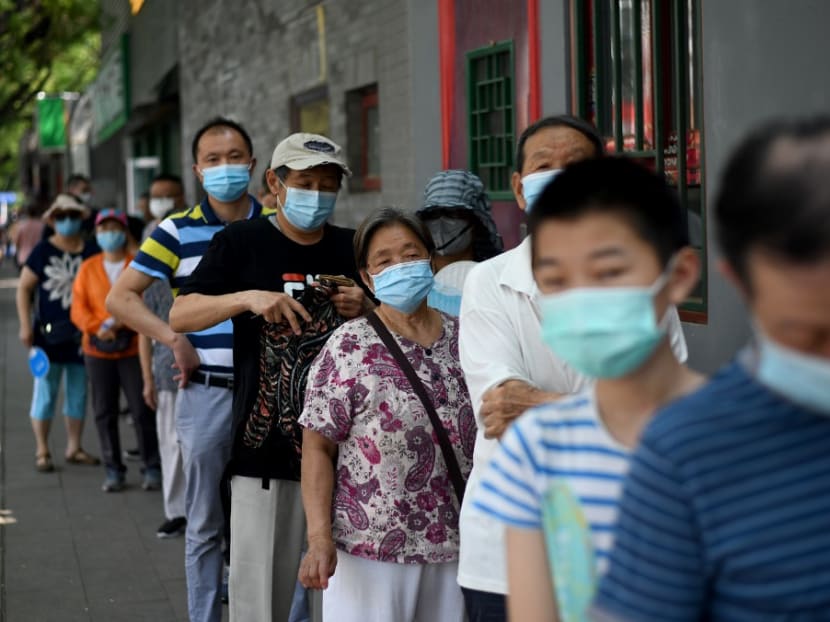 People wearing face masks queue to take a swab test during mass testing for Covid-19 in Beijing on June 21, 2020.