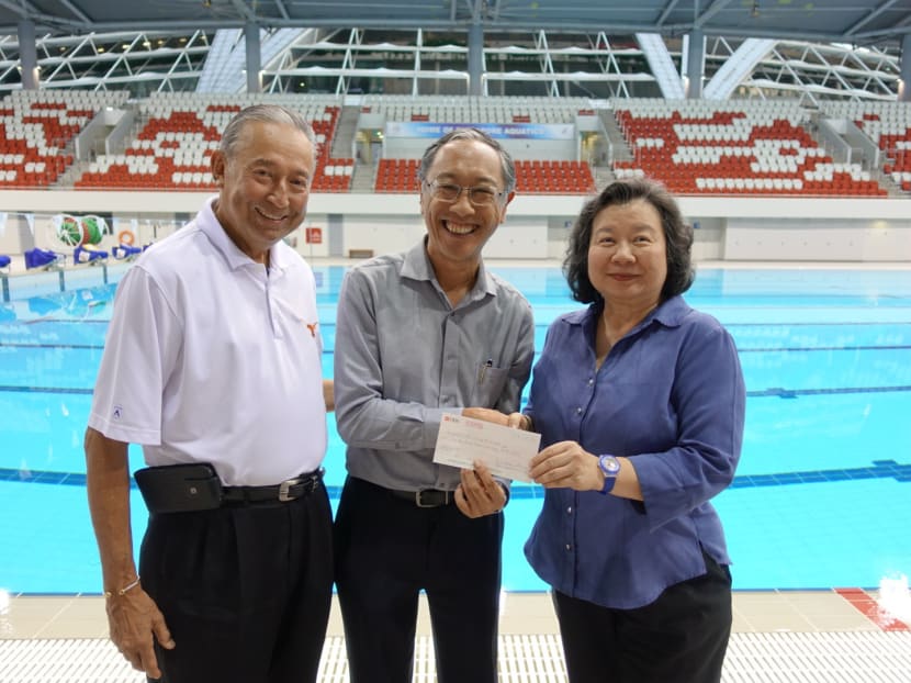 Colin (left) and May Schooling (right) presenting the S$200,000 cheque to Singapore Swimming Association president Lee Kok Choy. Photo: Singapore Swimming Association