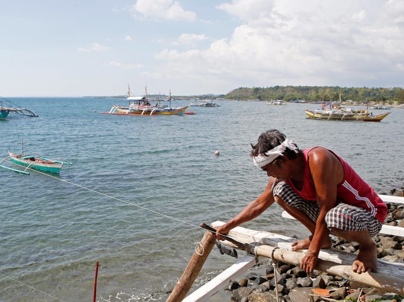A fisherman repairs his boat overlooking fishing boats that fish in the disputed Scarborough Shoal in the South China Sea, at Masinloc, Zambales, in the Philippines. Photo: REUTERS