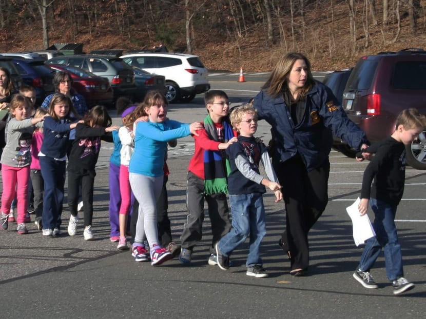 In this photo provided by the Newtown Bee, Connecticut State Police lead a line of children from the Sandy Hook Elementary School in Newtown on Friday, Dec 14, 2012 after a shooting at the school.  Photo: AP