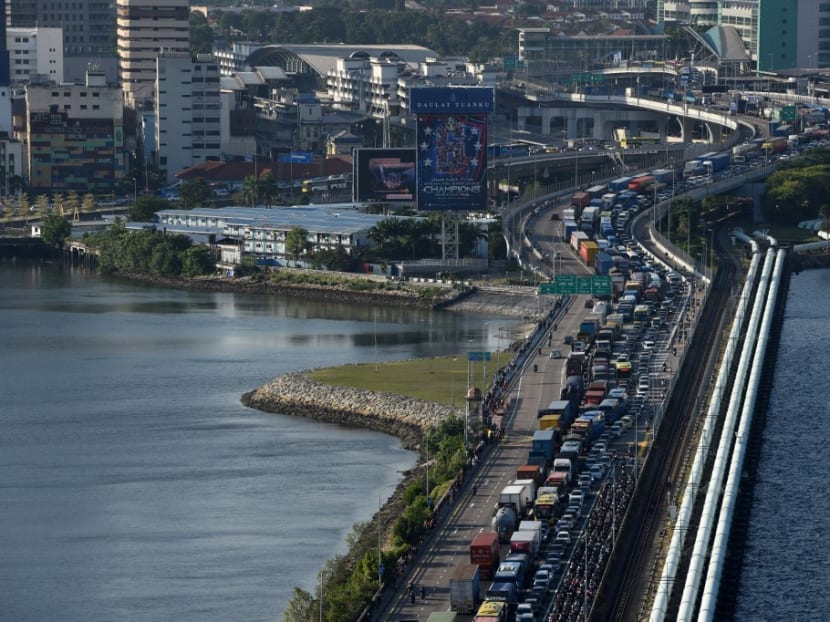 Vehicles form a long queue to enter Woodlands checkpoint in Singapore on March 17, 2020 from across the causeway of the southern Malaysian state of Johor.