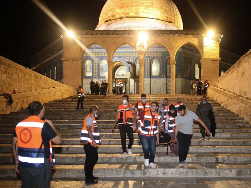 Palestinian medics evacuate a wounded person during clashes between Israeli security forces and Palestinian protestors in Jerusalem's al-Aqsa mosque compound on May 10, 2021.
