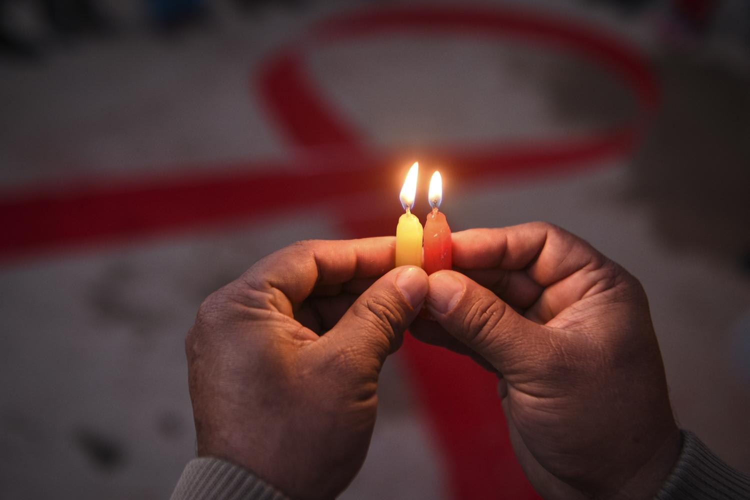 A volunteer lights candles forming the shape of a red ribbon during an awareness event on the eve of World Aids Day, in Kathmandu, Nepal, on Nov 30, 2020.