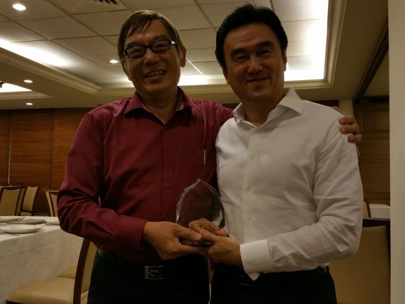 New Singapore Athletics president Ho Mun Cheong (left) presenting his predecessor Tang Weng Fei a momento for the latter's services to the sport. Photo: Low Lin Fhoong/TODAY