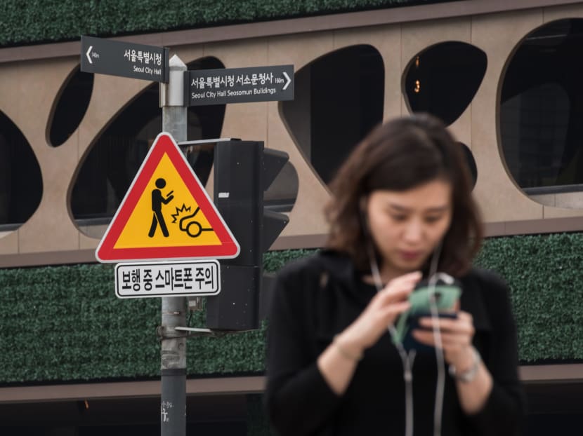 A sign advising pedestrians of the dangers of using smartphones while walking is displayed at an intersection in central Seoul on June 22, 2016. Photo: AFP