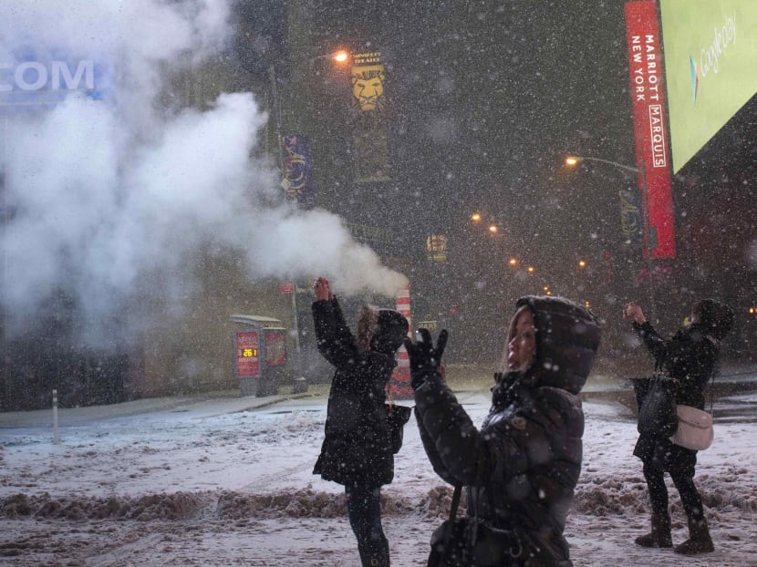 Female tourists using their smart phones to capture a snow storm in Times Square, New York. Reuters file photo