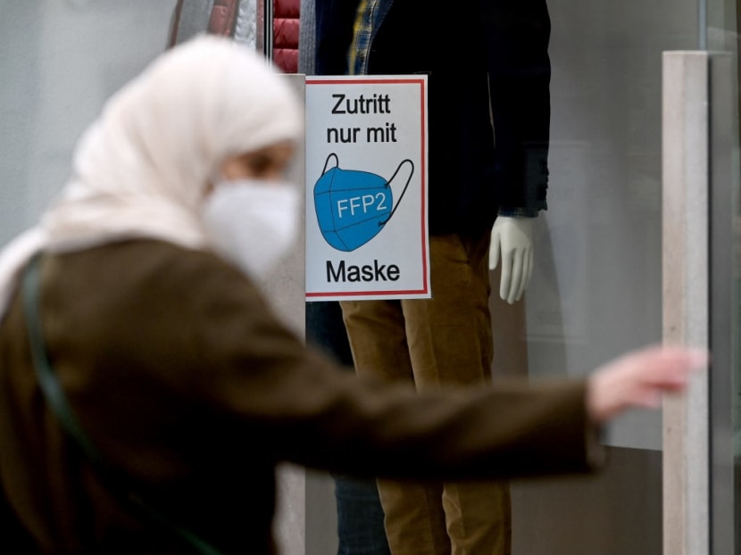 A woman walks past a shop window with a sign reading "Access only with FFP2 mask" in Salzburg, Austria, on Nov 15, 2021, during the ongoing Covid-19 pandemic.
