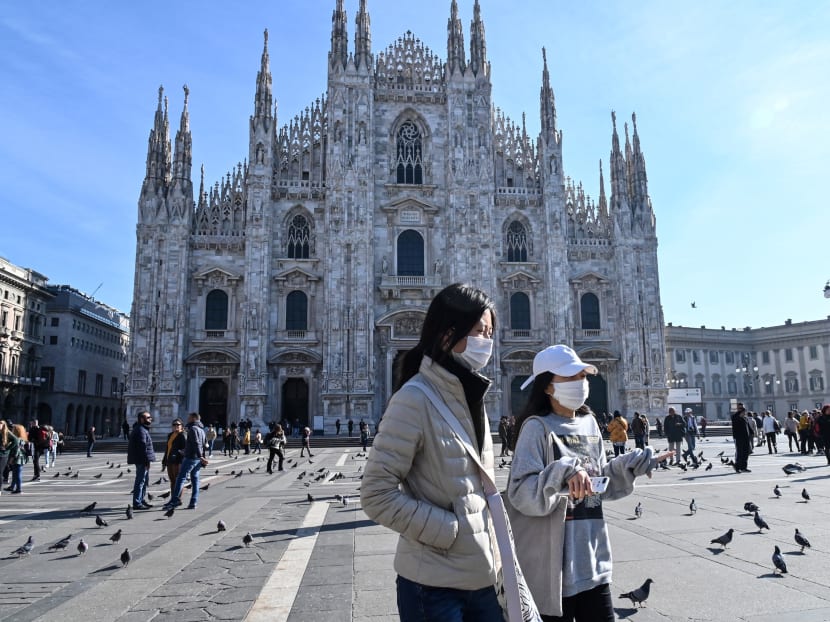 Two women wearing protective facemasks walk across the Piazza del Duomo in central Milan, Italy on Feb 24, 2020.