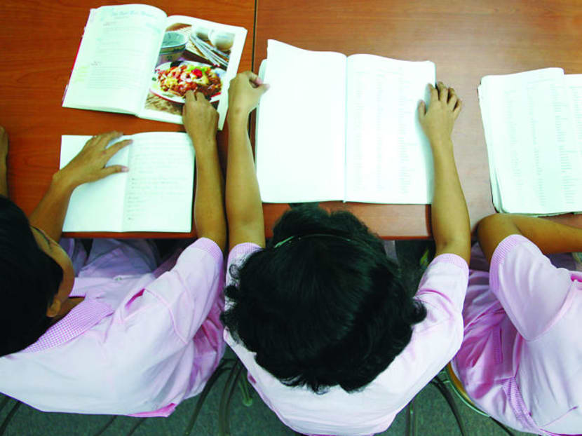 Domestic helpers doing their revision with language and recipe books at an agency.