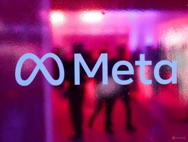 People walk behind a Meta Platforms logo during a conference in Mumbai, India, September 20, 2023.